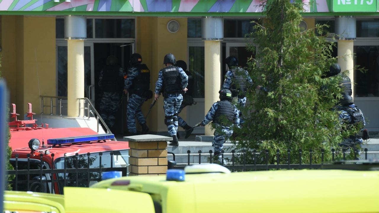 Rettungswagen und Polizeifahrzeuge mit Blaulicht und Sirene: der Tatort in der russischen Stadt Kasan nach dem tödlichen Angriff.