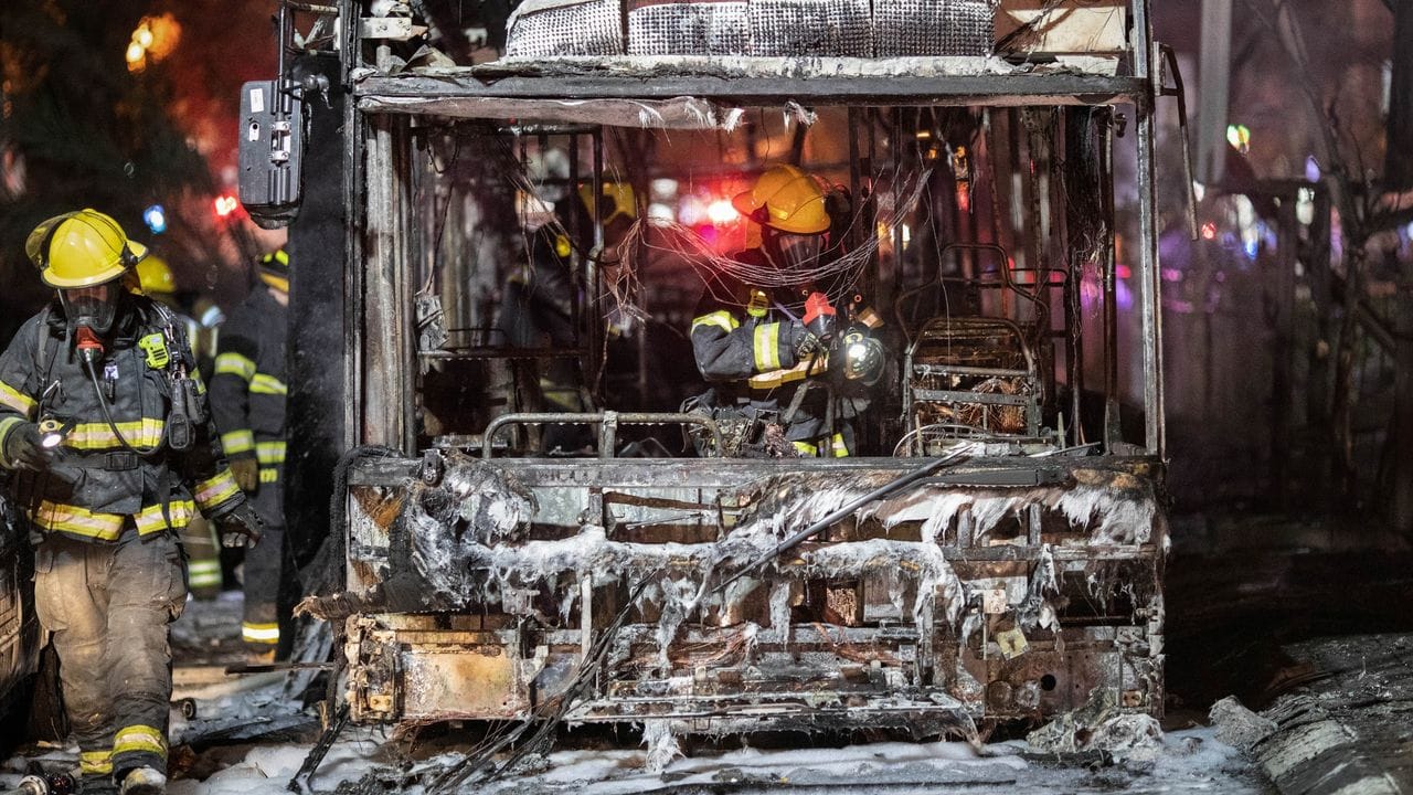 Israelische Feuerwehrleute untersuchen einen völlig ausgebrannten Bus, nachdem dieser von einer Rakete getroffen worden war.