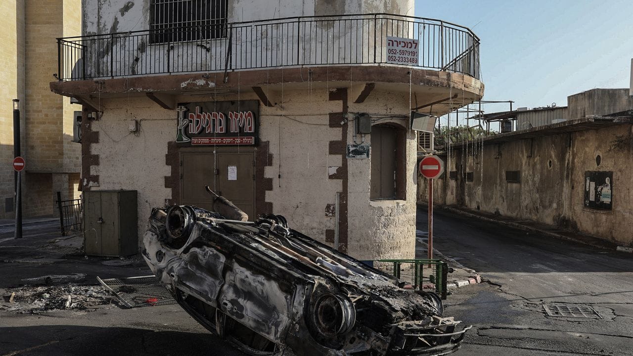 Ein verbranntes Auto liegt nach Zusammenstößen zwischen Polizisten und arabischen Israelis auf einer Straße in Lod, rund 20 Kilometer östlich von Tel Aviv.