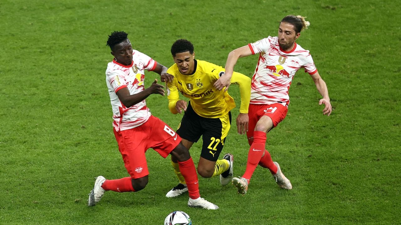 Dortmunds Mittelfeldspieler Jude Bellingham (M) wird von Leipzigs Amadou Haidara (l) und Kevin Kampl (r) in die Zange genommen.
