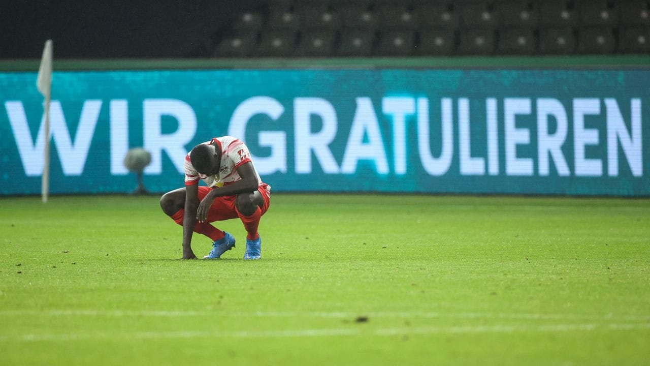 Leipzigs Dayot Upamecano hockt nach Spielende enttäuscht auf dem Spielfeld.