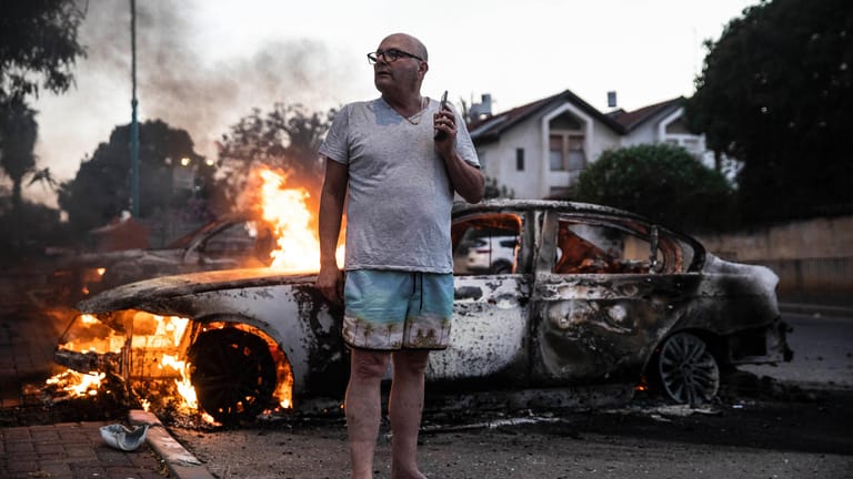 Lod in Israel: Ein Mann steht vor seinem brennenden Auto, nachdem die Hamas erklärte, 130 Raketen aus dem Gazastreifen nach Tel Aviv und Zentralisrael abgefeuert zu haben.