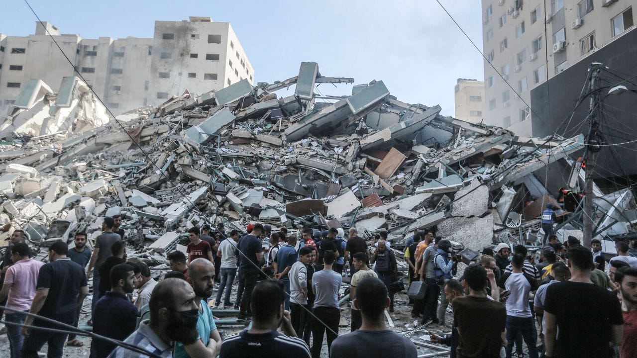 Palästinenser stehen vor den Trümmern eines Gebäudes, in dem verschiedene internationale Medien untergebracht waren, darunter auch die Associated Press und Al-Dschasira, nach einem israelischen Luftangriff.