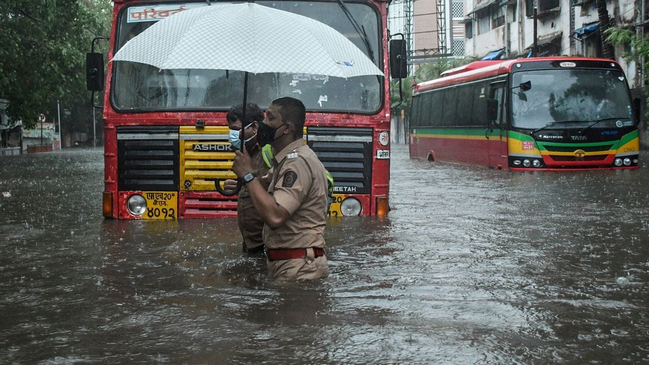 Ein Polizist hilft in Mumbai einem Fahrer eines öffentlichen Verkehrsmittels, eine überschwemmte Straße zu überqueren.