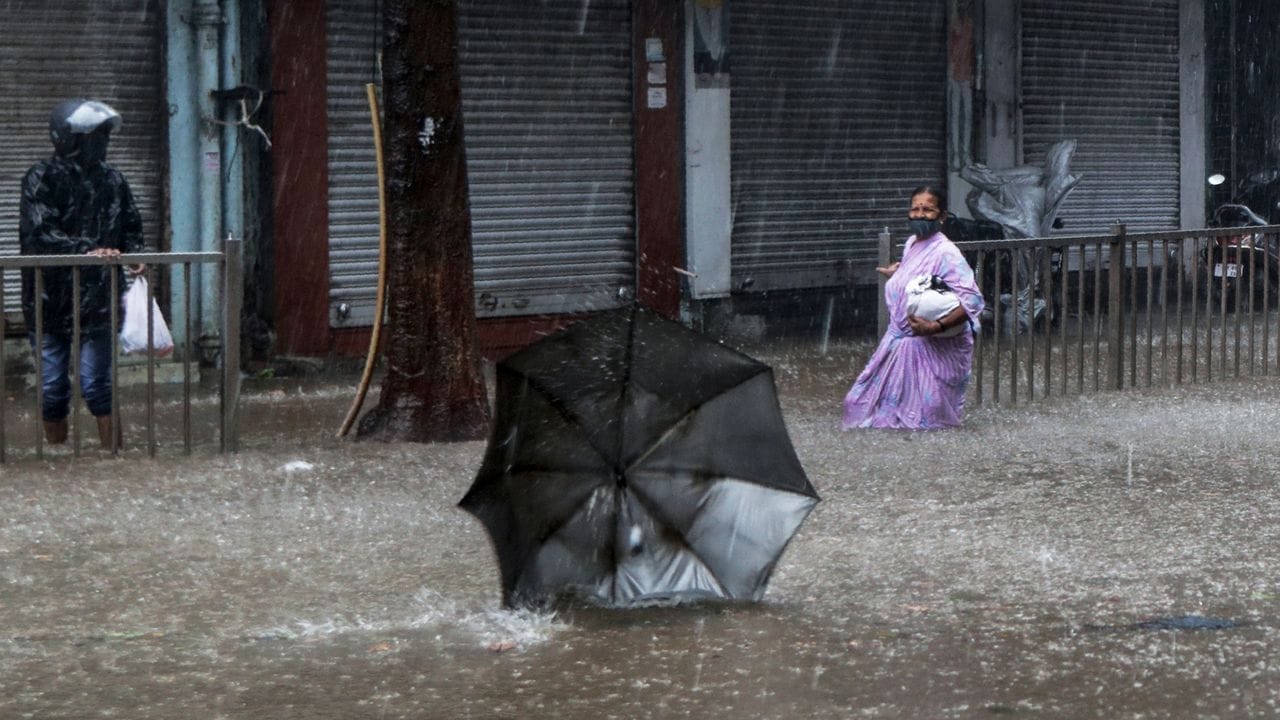 Eine Frau sieht hilflos zu, wie ihr Regenschirm während eines starken Regens im Wind davonfliegt.