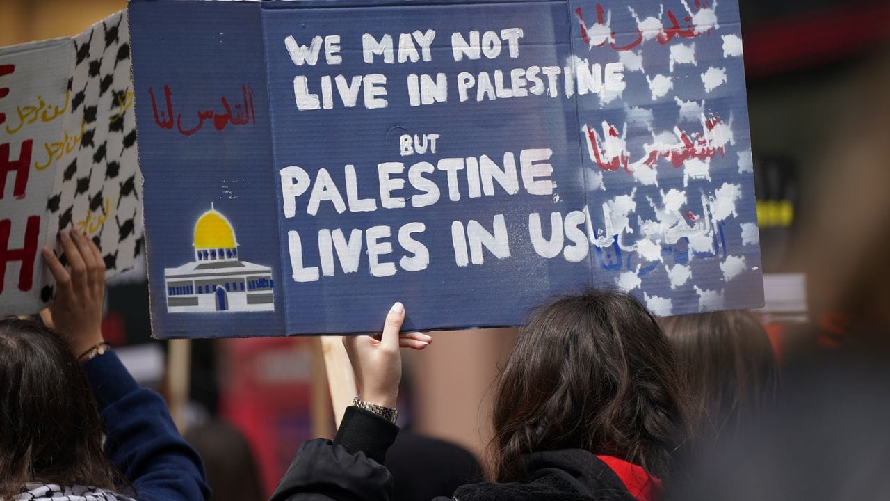 Demo-Schild: "Wir leben vielleicht nicht in Palästina, aber Palästina lebt in uns".