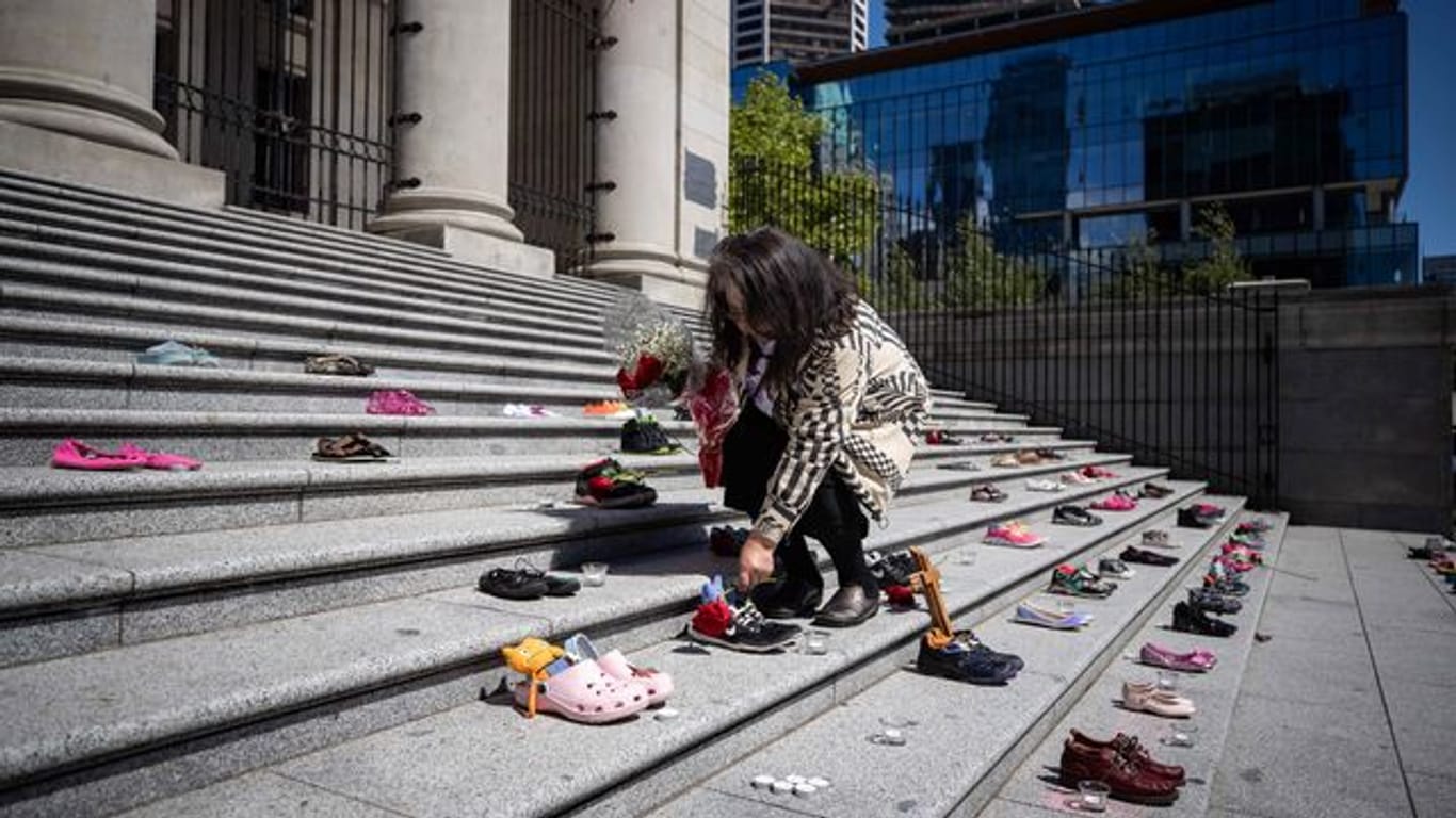 Eine Angehörige einer indigenen Volksgruppe legt eine Rose auf eines von 215 Paar Kinderschuhen auf den Stufen der Vancouver Art Gallery.