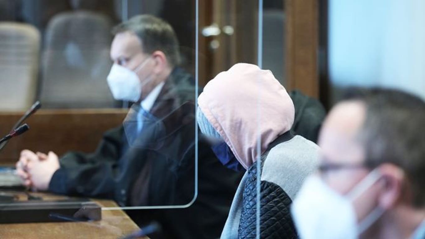 Die angeklagte Mutter (M) zwischen Anwälten im Gerichtssaal in Köln.