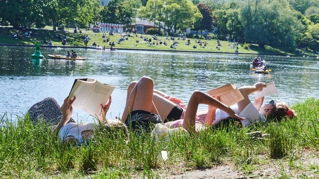 Drei Frauen liegen auf der Wiese am Landwehrkanal in Berlin und lesen Bücher. Drei Frauen liegen auf der Wiese am Landwehrkanal in Berlin und lesen Bücher.