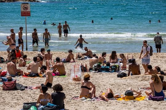 Menschen verbringen den Tag in der Sonne am Strand von Tel Aviv.