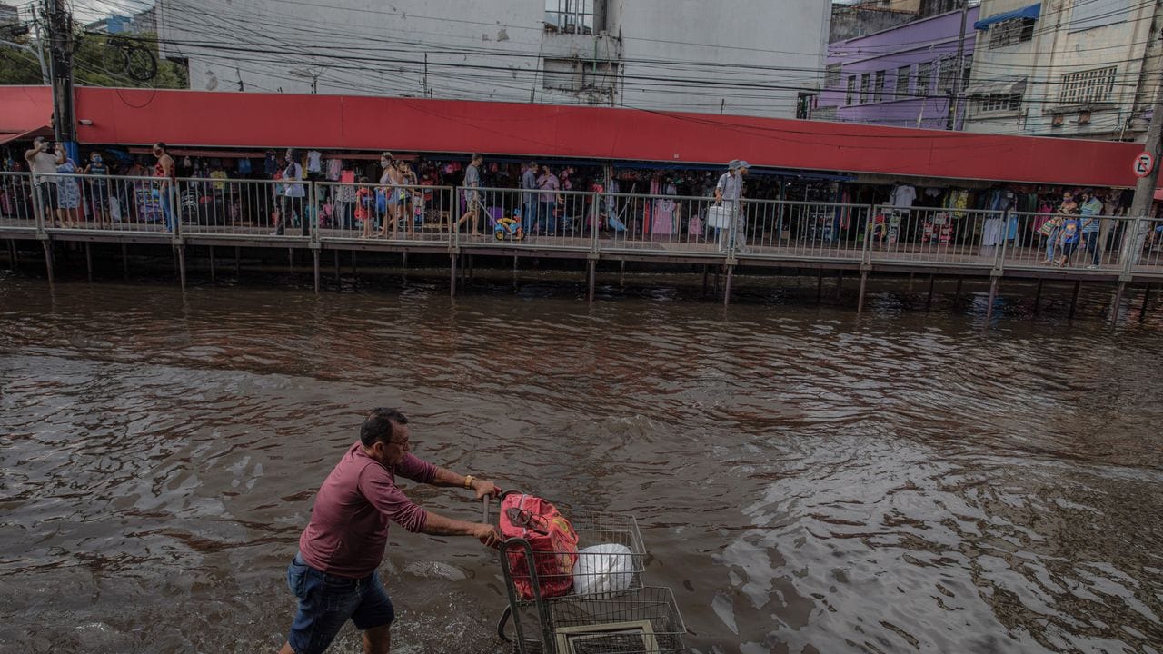 Ein Mann schiebt einen Einkaufswagen durch eine überschwemmte Straße in Manaus.