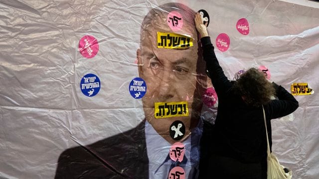 Ein Plakat mit dem Konterfei von Israels Premierminister Netanjahu wird mit Aufklebern überklebt. Ein Plakat mit dem Konterfei von Israels Premierminister Netanjahu wird mit Aufklebern überklebt.