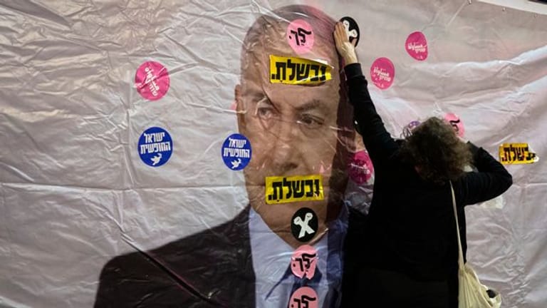Ein Plakat mit dem Konterfei von Israels Premierminister Netanjahu wird mit Aufklebern überklebt.