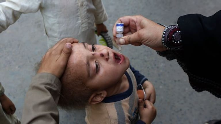 Ein Mitarbeiter des Gesundheitswesens gibt einem Kind eine Schluckimpfung gegen Polio (Kinderlähmung).