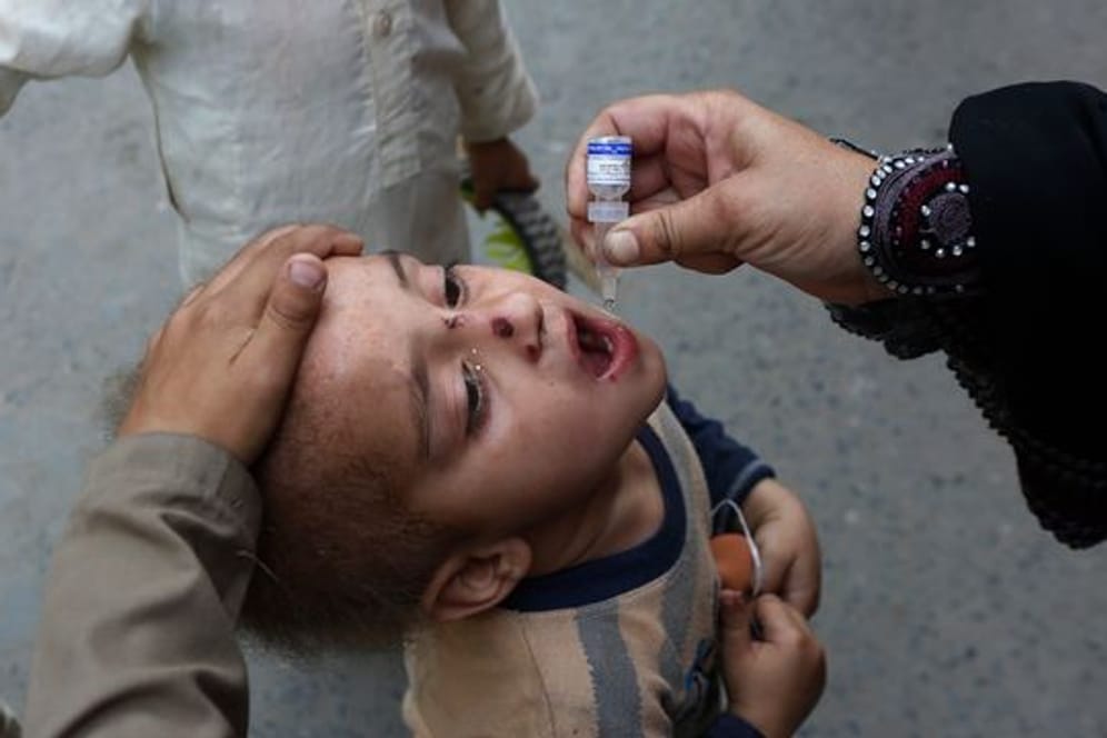 Ein Mitarbeiter des Gesundheitswesens gibt einem Kind eine Schluckimpfung gegen Polio (Kinderlähmung).