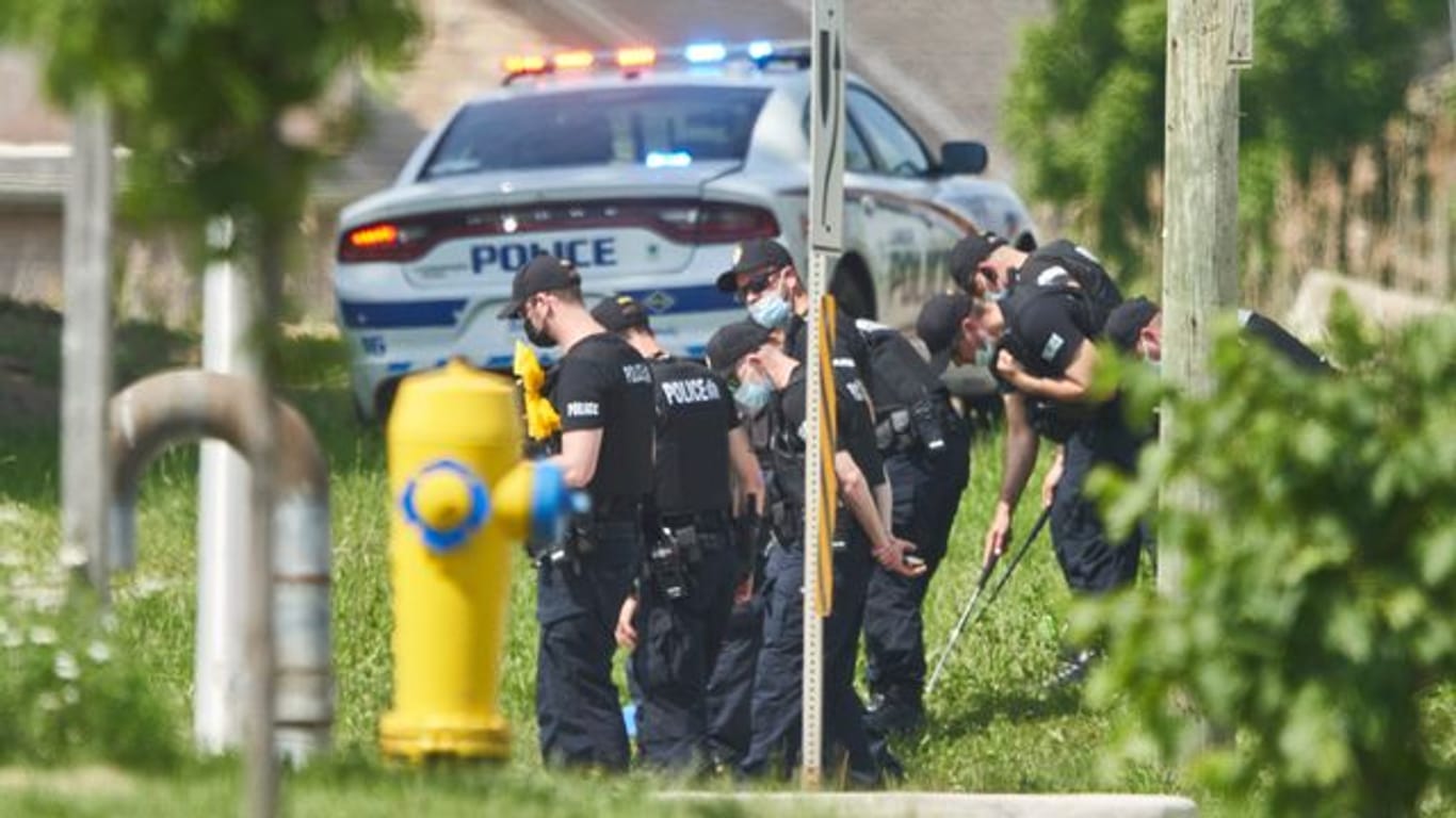 Polizisten in Reihe untersuchen den Tatort eines Autounfalls in London, Ontario.