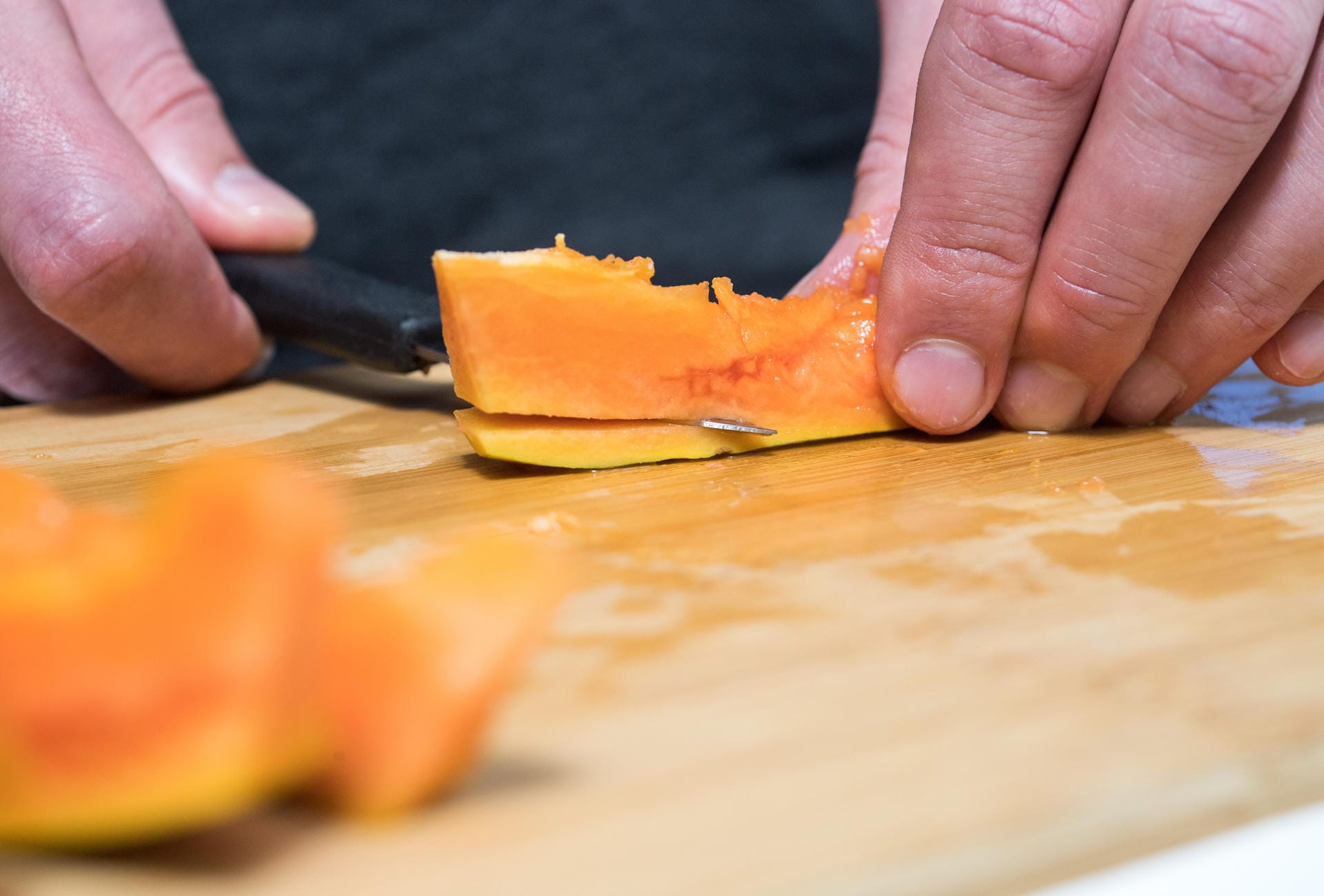 5. Schritt: Zeit für einen Messer-Wechsel: Zum Lösen des Fruchtfleischs benötigen Sie eine kurze Klinge. Damit gleiten Sie vorsichtig zwischen Schale und Fleisch entlang. Die Spalten liegen so auf dem Brett, dass die Schale nach unten zeigt.