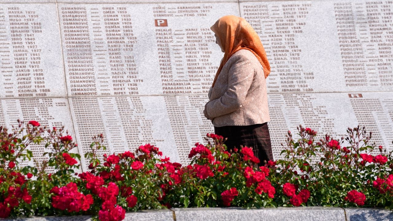 Eine Frau betrachtet auf dem Gedenkfriedhof für die Opfer des Massakers von Srebenica Namen von Getöteten. Eine Frau betrachtet auf dem Gedenkfriedhof für die Opfer des Massakers von Srebenica Namen von Getöteten.