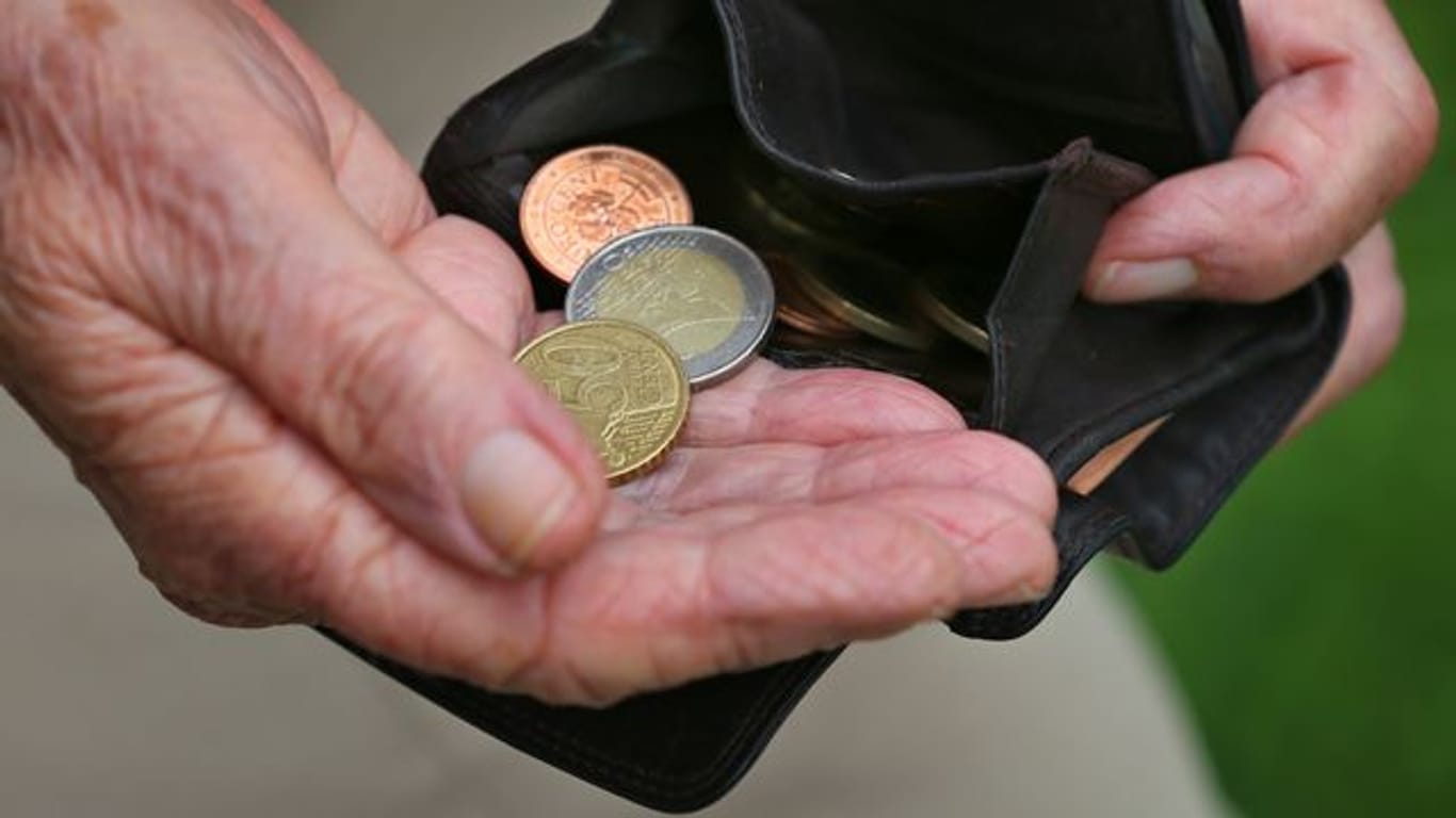 Eine Rentnerin hält einen Geldbeutel mit verschiedenen Euromünzen (gestellte Szenen).