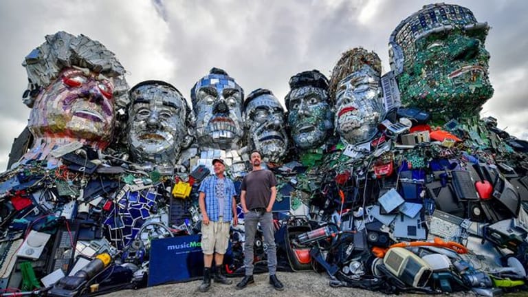 Die Künstler Alex Wreckage (l) und Joe Rush von der "Mutoid Waste Company" stehen vor dem G7-Gipfel in Cornwall vor ihrem Kunstwerk "Mount Trashmore" am Strand bei Gwithian.