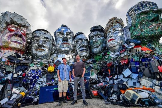 Die Künstler Alex Wreckage (l) und Joe Rush von der "Mutoid Waste Company" stehen vor dem G7-Gipfel in Cornwall vor ihrem Kunstwerk "Mount Trashmore" am Strand bei Gwithian.