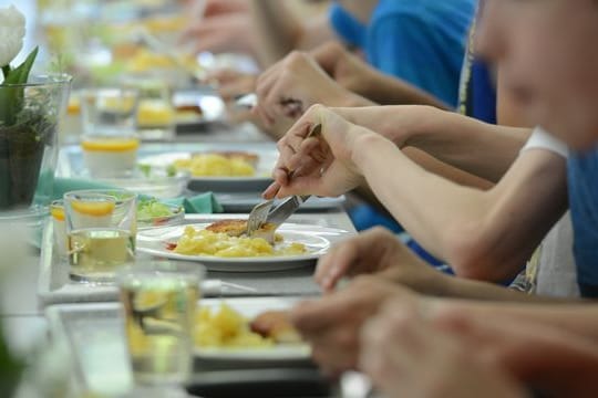 Schüler einer Ganztagsschule essen zusammen in der Mensa.