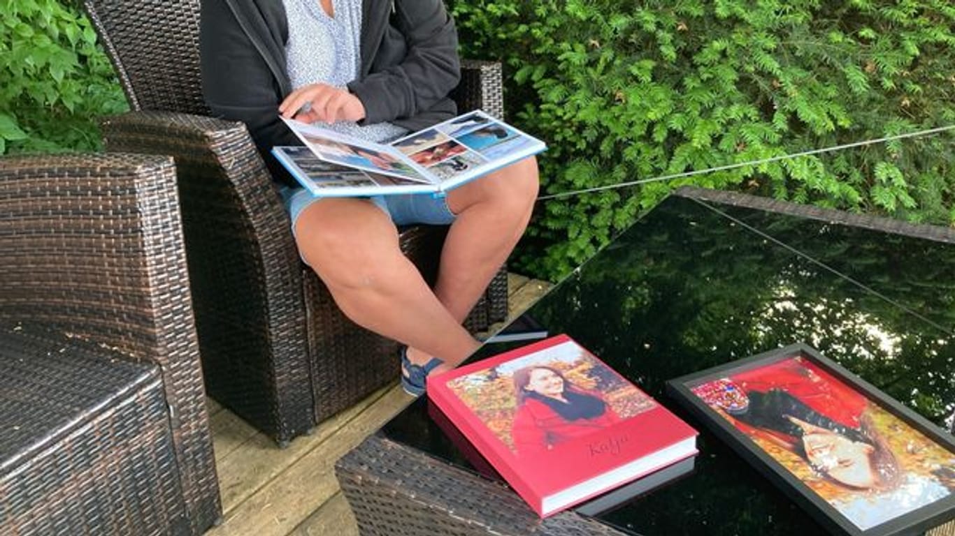 Petra Lieser sitzt mit Fotobüchern über ihre Tochter in ihrem Garten.