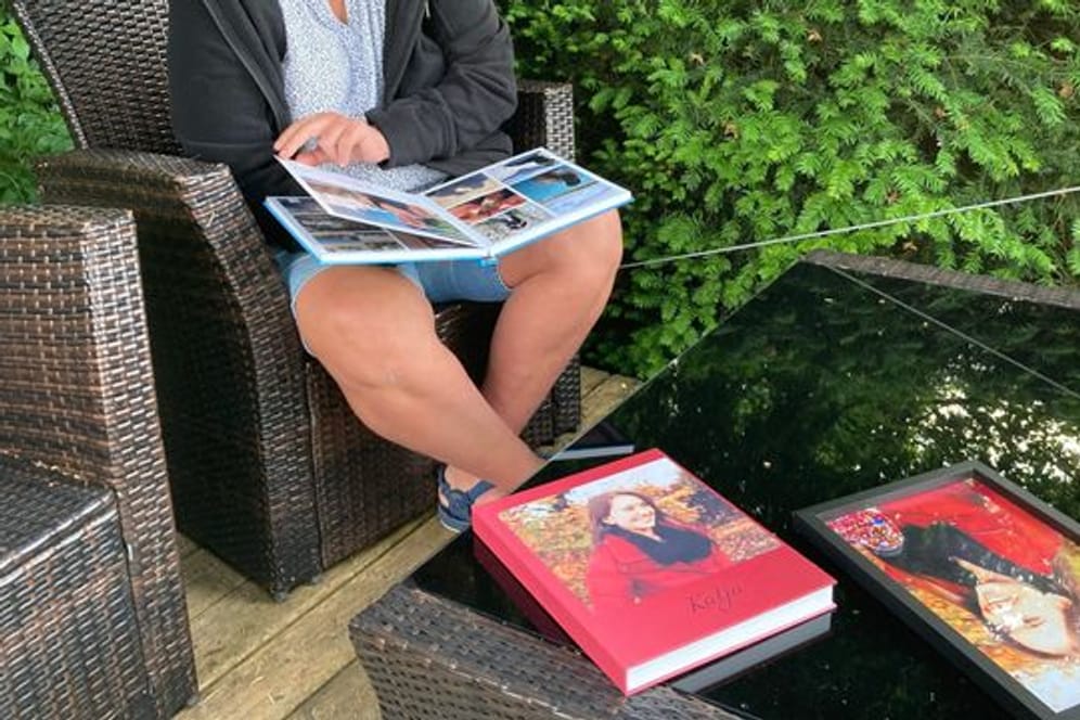 Petra Lieser sitzt mit Fotobüchern über ihre Tochter in ihrem Garten.