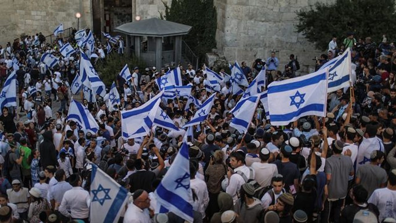 Menschen schwenken israelische Fahnen bei dem umstrittenen Flaggenmarsch in Jerusalem, der von rechtsgerichteten Nationalisten in Israel organisiert worden ist.