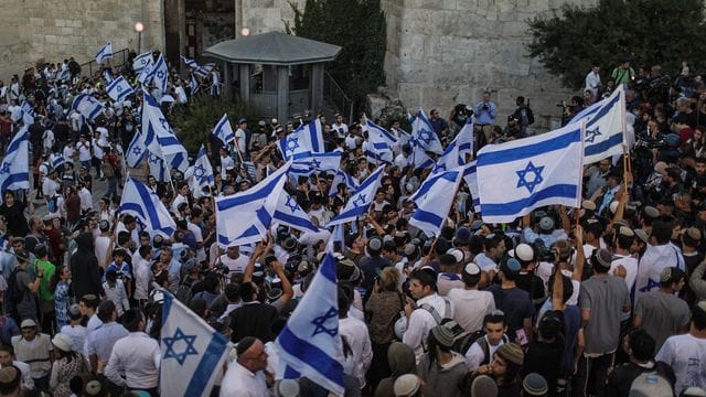 Menschen schwenken israelische Fahnen bei dem umstrittenen Flaggenmarsch in Jerusalem, der von rechtsgerichteten Nationalisten in Israel organisiert worden ist. Menschen schwenken israelische Fahnen bei dem umstrittenen Flaggenmarsch in Jerusalem, der von rechtsgerichteten Nationalisten in Israel organisiert worden ist.