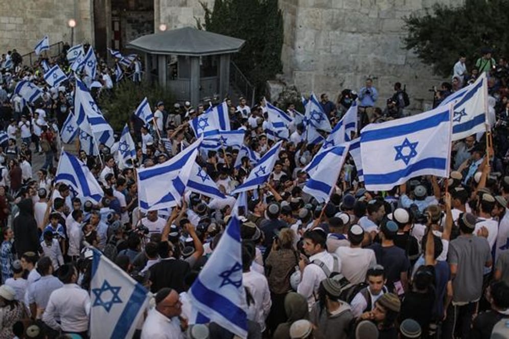Menschen schwenken israelische Fahnen bei dem umstrittenen Flaggenmarsch in Jerusalem, der von rechtsgerichteten Nationalisten in Israel organisiert worden ist.