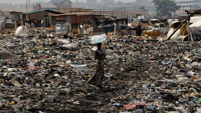 Eine Frau steht auf der Freifläche hinter dem Schrottplatz von Agbogbloshie in Ghana.