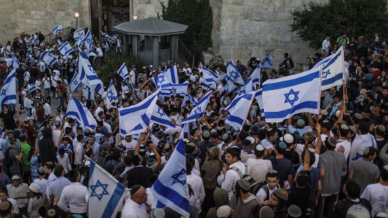 Menschen schwenken israelische Fahnen bei dem umstrittenen Flaggenmarsch in Jerusalem, der von rechtsgerichteten Nationalisten in Israel organisiert worden ist. Menschen schwenken israelische Fahnen bei dem umstrittenen Flaggenmarsch in Jerusalem, der von rechtsgerichteten Nationalisten in Israel organisiert worden ist.