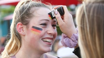 Die letzten Vorbereitungen: Henrike (l) bekommt von ihrer Freundin Franzi vor dem Public Viewing in Hamburg die Deutschland-Farben auf die Stirn gemalt..