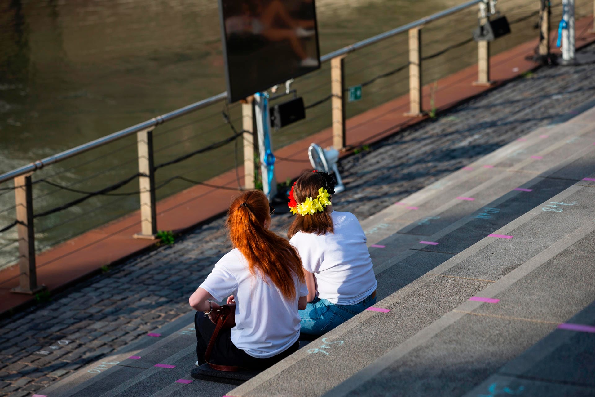 Zwei Frauen sitzen im Open-Air-Kino in der Südstadt: Der Kopfschmuck in den Deutschlandfarben soll die Unterstützung für ihr Team ausdrücken.