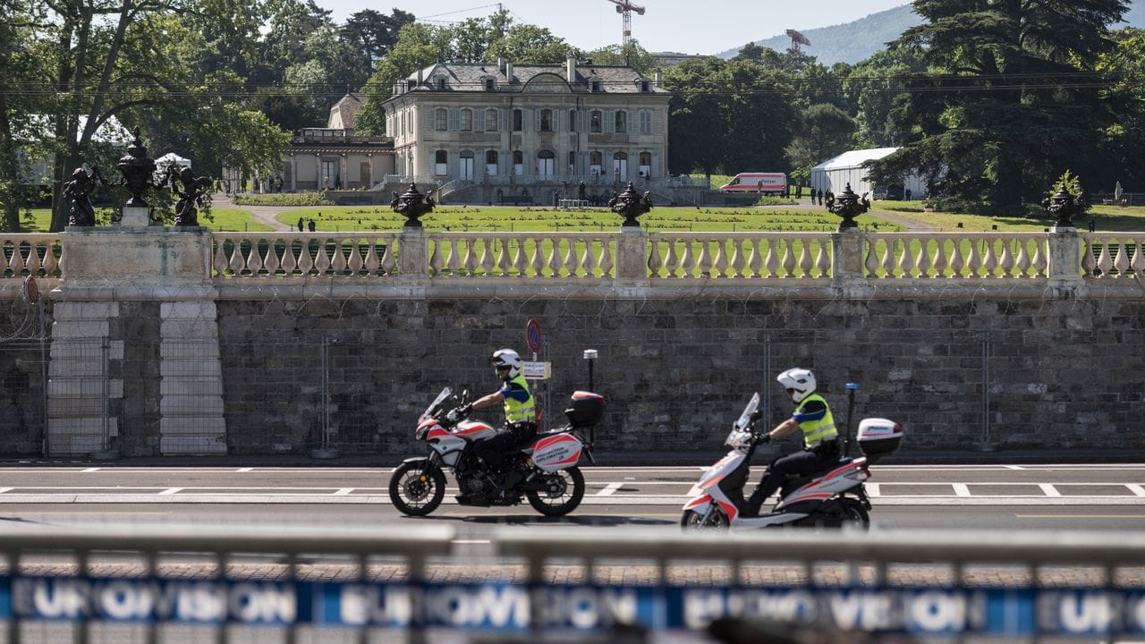 Polizisten auf Motorrädern fahren an der Villa La Grange vorbei, wo sich Biden und Putin treffen.