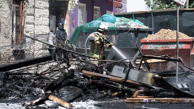 Ein Feuerwehrmann löscht eine brennende Barrikade in der Rigaer Straße in Berlin-Friedrichshain.