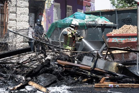 Ein Feuerwehrmann löscht eine brennende Barrikade in der Rigaer Straße in Berlin-Friedrichshain.