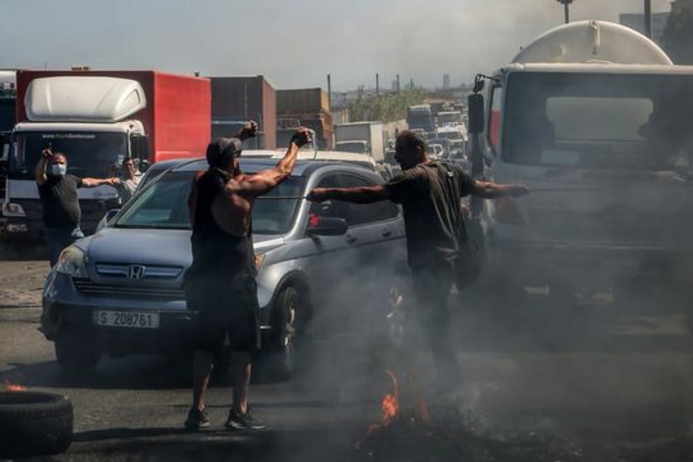 Demonstranten verhindern die Durchfahrt von Autos, während sie eine Hauptstraße, die Beirut mit dem Südlibanon verbindet, mit brennenden Reifen blockieren.