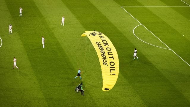 Ein Greenpeace-Aktivist landet mit einem Motorschirm-Flieger bei einer Protestaktion auf dem Spielfeld. Ein Greenpeace-Aktivist landet mit einem Motorschirm-Flieger bei einer Protestaktion auf dem Spielfeld.