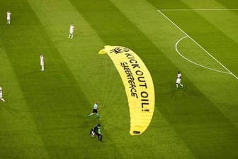 Ein Greenpeace-Aktivist landet mit einem Motorschirm-Flieger bei einer Protestaktion auf dem Spielfeld.