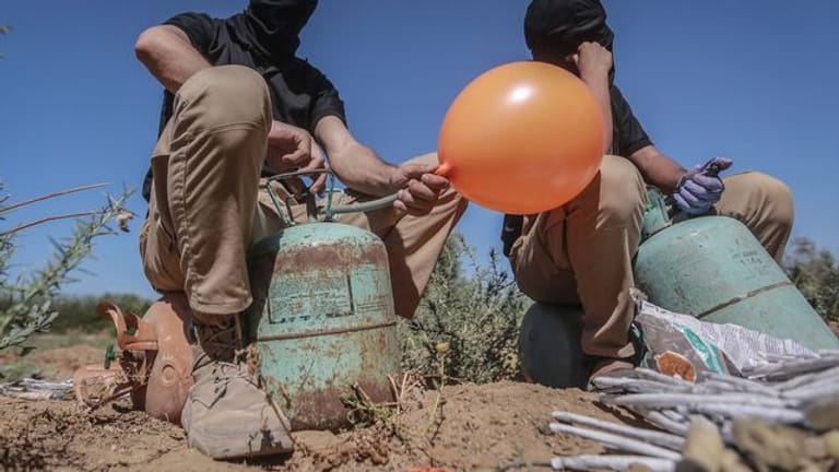 Maskierte Palästinenser präparieren Brandballons.