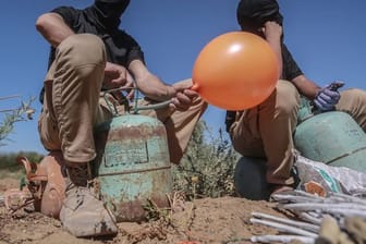 Maskierte Palästinenser präparieren Brandballons.