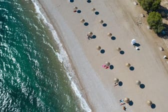 An einem Strand südlich von Athen stehen Sonnenschirme für Strandbesucher bereit.