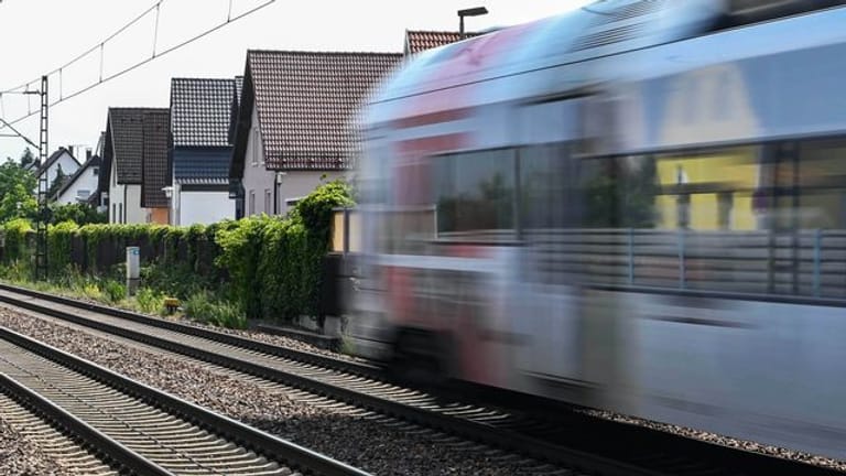 Auf der Bahnstrecke Karlsruhe-Mannheim fährt ein Zug an Häusern vorbei.