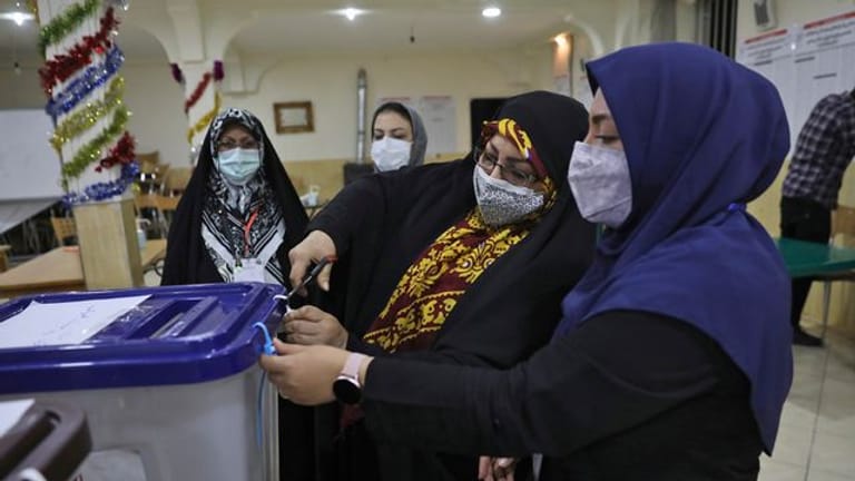 Wahlhelferinnen öffnen eine Wahlurne in einem Wahllokal in Teheran.