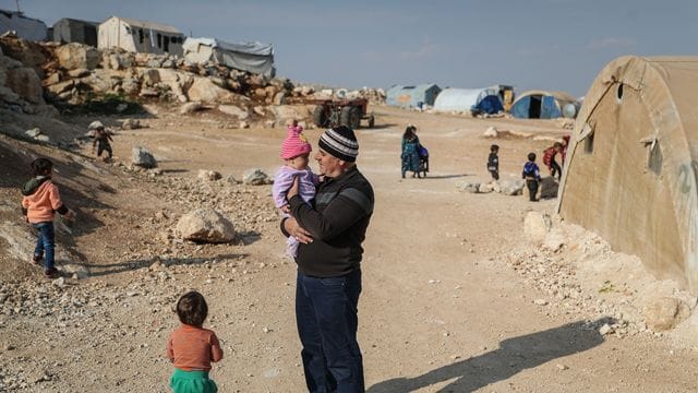 Ein Mann steht mit seinen Kindern in einem Flüchtlingslager in der Provinz Idlib.