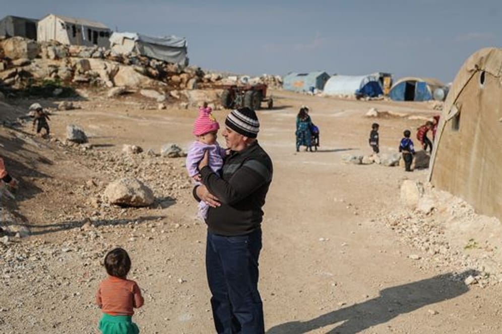 Ein Mann steht mit seinen Kindern in einem Flüchtlingslager in der Provinz Idlib.