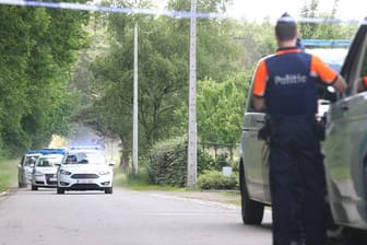 Polizeifahrzeuge fahren hinter einem abgesperrten Bereich in der Nähe des Fundorts der Leiche des gesuchten Conings im Waldgebiet Dilserbos.