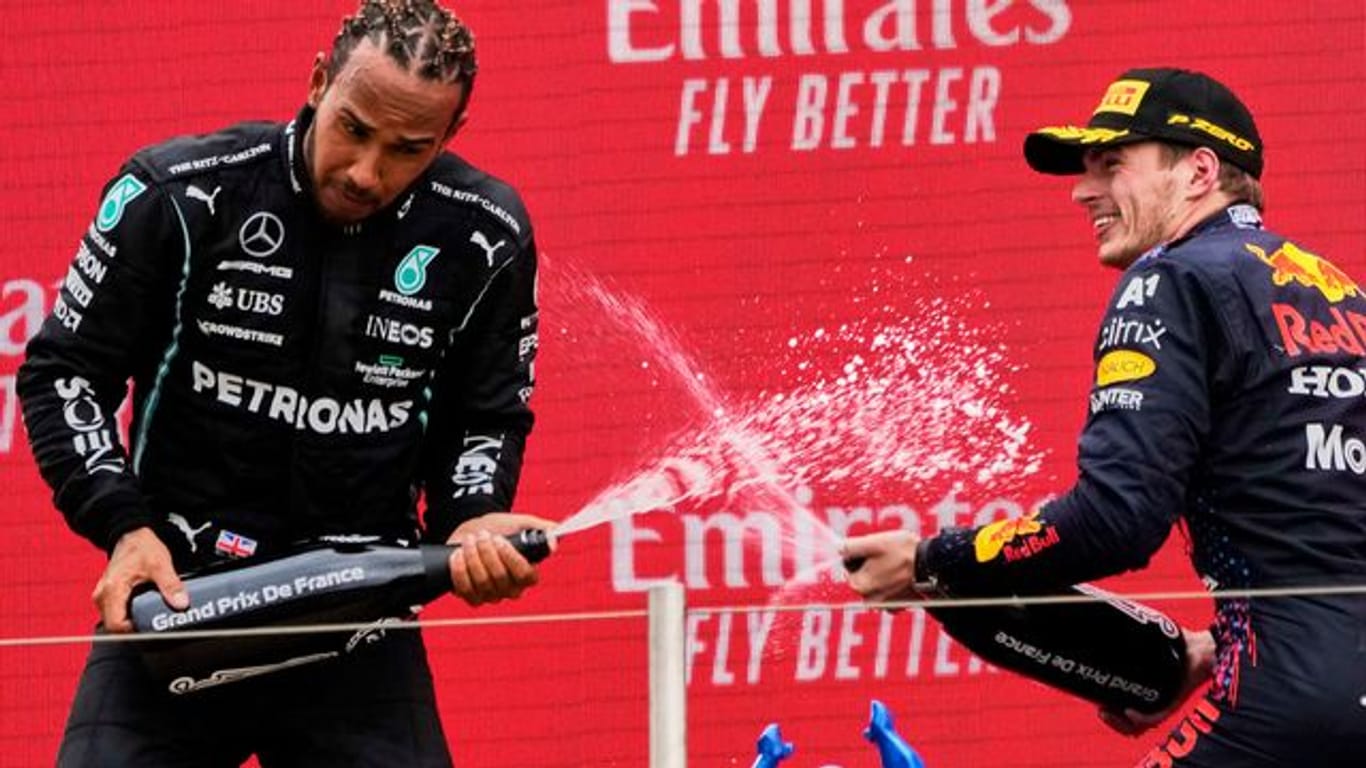 Sieger Max Verstappen (r) und der Zweitplatzierte Lewis Hamilton lassen auf dem Podium den Champagner spritzen.